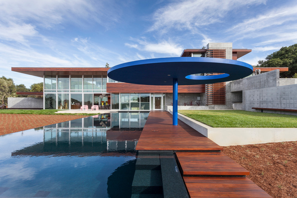 Стильный дизайн: большой прямоугольный бассейн-инфинити на заднем дворе в стиле модернизм с фонтаном и настилом - последний тренд
