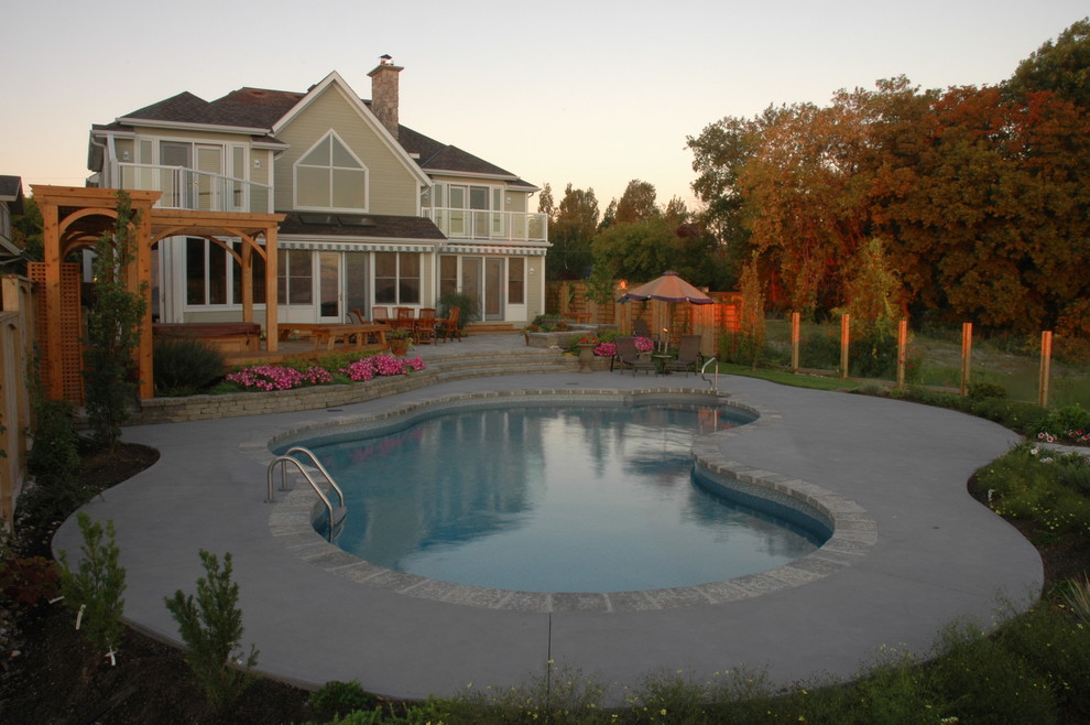Cette image montre une grande piscine naturelle et arrière design en forme de haricot avec une dalle de béton.