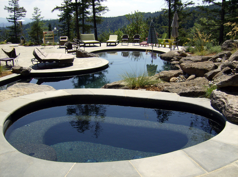 Exemple d'une très grande piscine arrière éclectique sur mesure avec un bain bouillonnant et des pavés en pierre naturelle.
