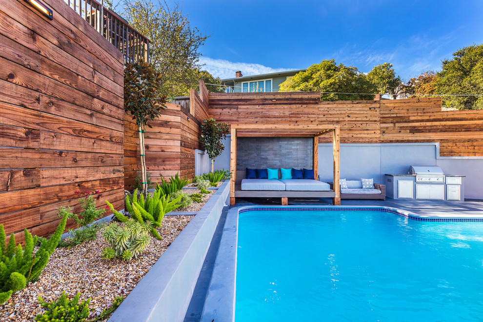 Exemple d'un grand couloir de nage arrière tendance sur mesure avec une terrasse en bois.