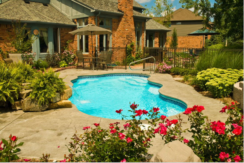 Ejemplo de piscina rural de tamaño medio a medida en patio trasero con suelo de hormigón estampado