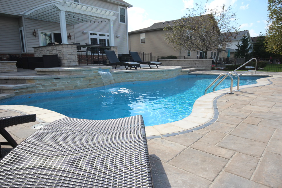 Modelo de piscinas y jacuzzis alargados actuales grandes a medida en patio trasero con adoquines de ladrillo