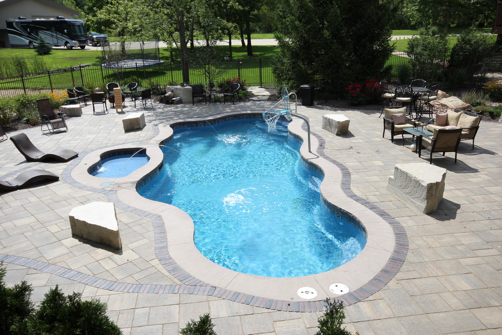 Modelo de piscinas y jacuzzis alargados actuales grandes a medida en patio trasero con adoquines de ladrillo
