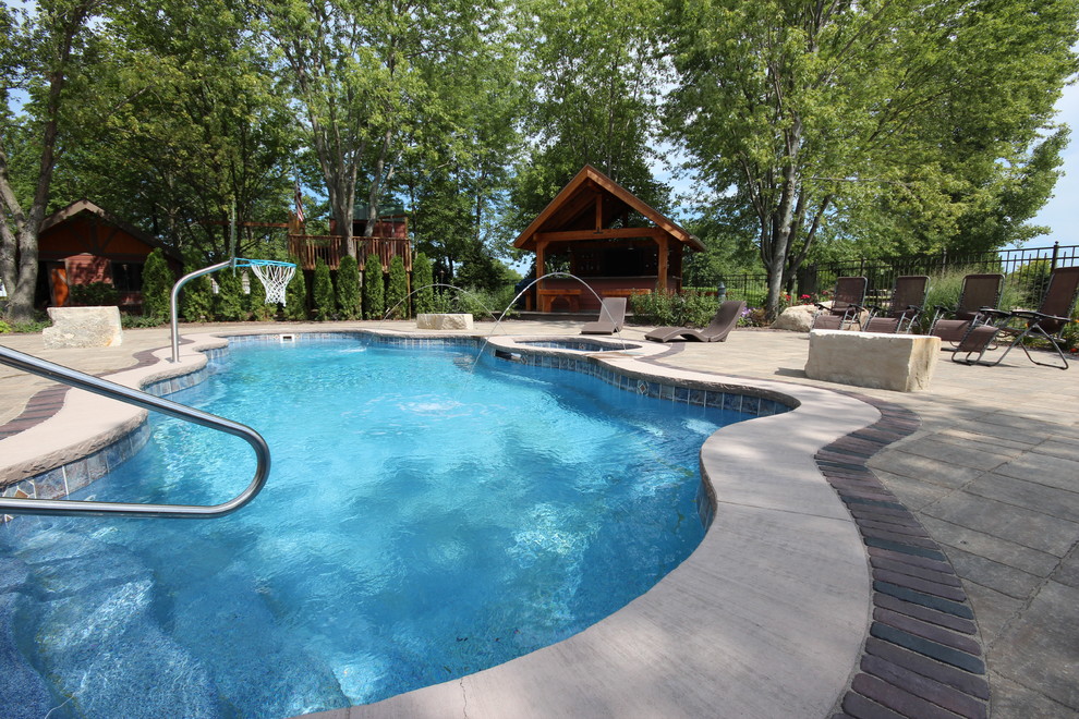 Foto de piscinas y jacuzzis alargados contemporáneos grandes a medida en patio trasero con adoquines de ladrillo