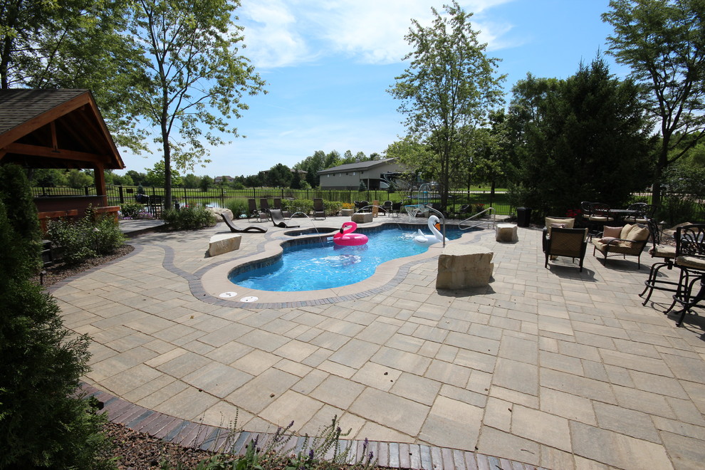 Esempio di una grande piscina monocorsia contemporanea personalizzata dietro casa con una vasca idromassaggio e pavimentazioni in mattoni