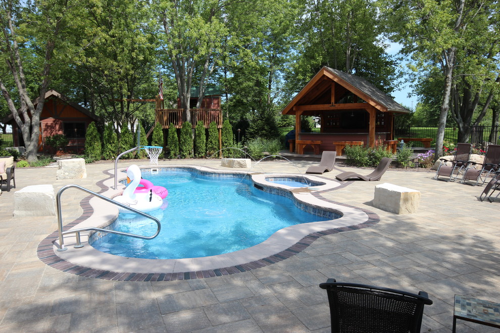 Large contemporary back custom shaped lengths hot tub in Chicago with brick paving.
