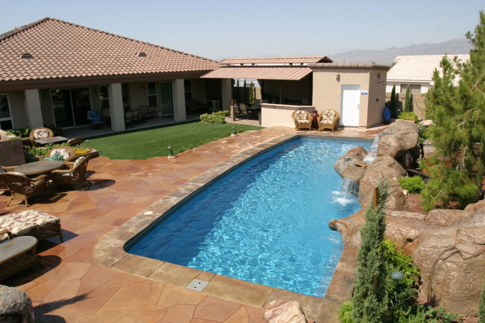 Exempel på en stor amerikansk rektangulär pool på baksidan av huset, med en fontän och naturstensplattor