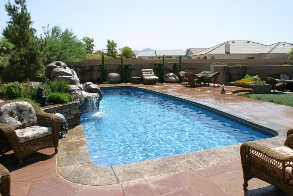 Réalisation d'une grande piscine arrière sud-ouest américain rectangle avec un point d'eau et des pavés en pierre naturelle.