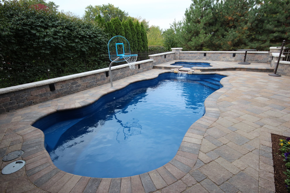 Imagen de piscinas y jacuzzis clásicos renovados grandes a medida en patio trasero con adoquines de ladrillo