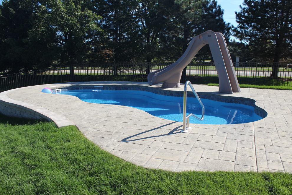 Пример оригинального дизайна: бассейн среднего размера, произвольной формы на заднем дворе в классическом стиле с домиком у бассейна и покрытием из каменной брусчатки