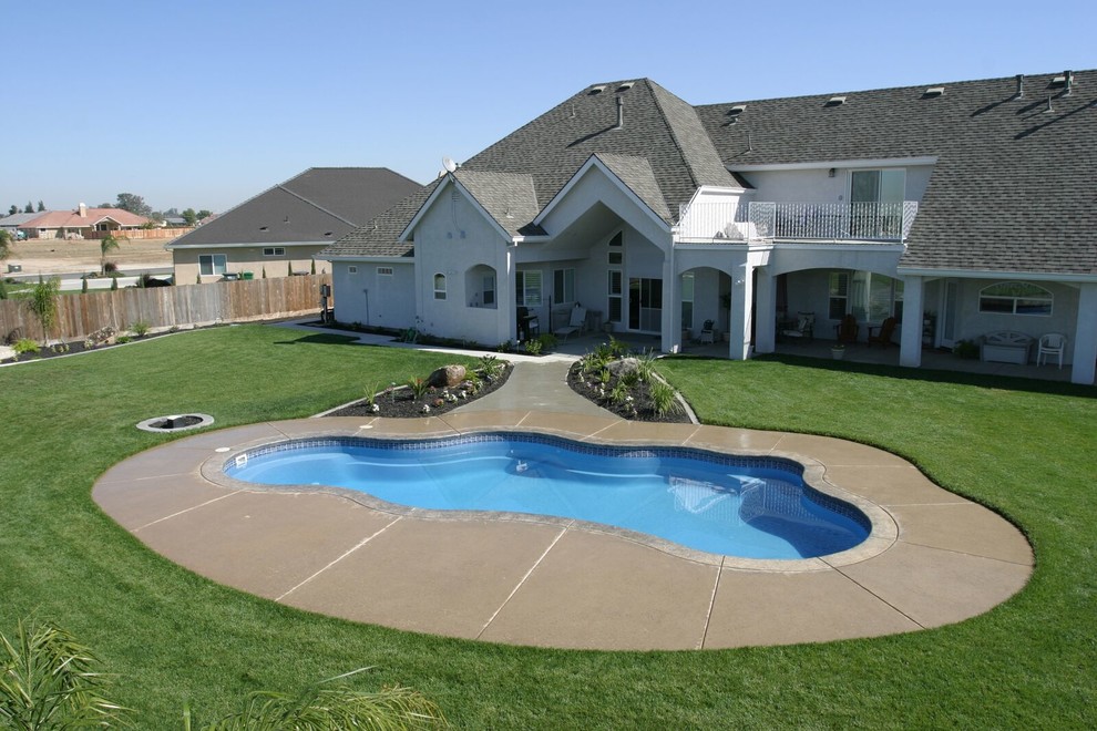 На фото: бассейн среднего размера, произвольной формы на заднем дворе в стиле модернизм с покрытием из бетонных плит с