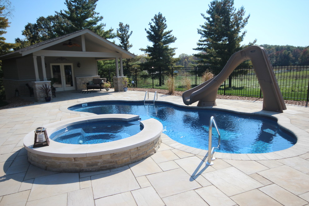 Diseño de piscina con tobogán clásica renovada de tamaño medio a medida en patio trasero con adoquines de ladrillo