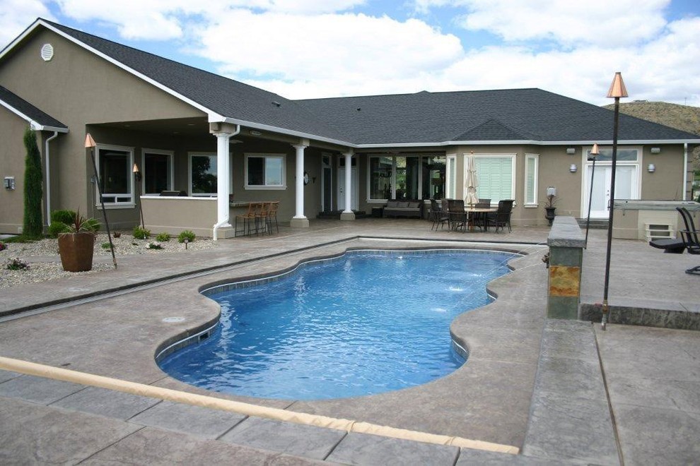 Photo of a medium sized contemporary back custom shaped swimming pool in Seattle with a water feature and stamped concrete.
