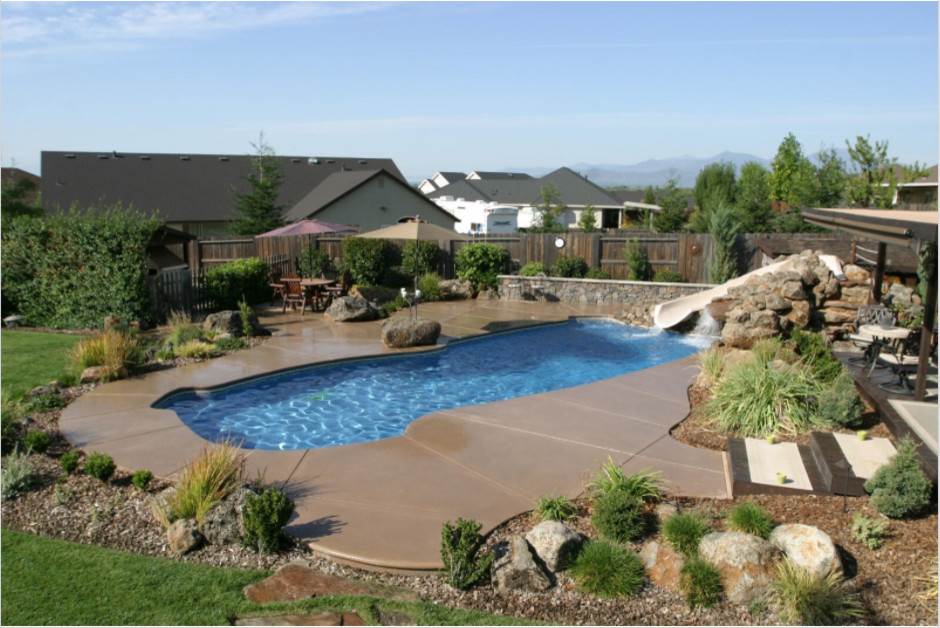 Foto de piscina con tobogán rústica de tamaño medio a medida en patio trasero con adoquines de hormigón