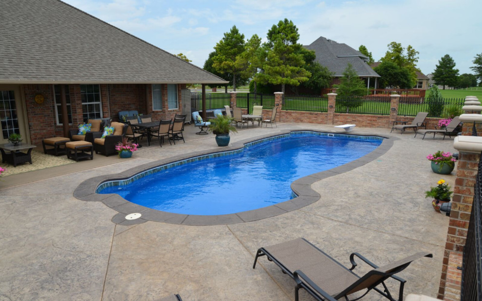 Exempel på en mellanstor lantlig anpassad pool på baksidan av huset, med stämplad betong