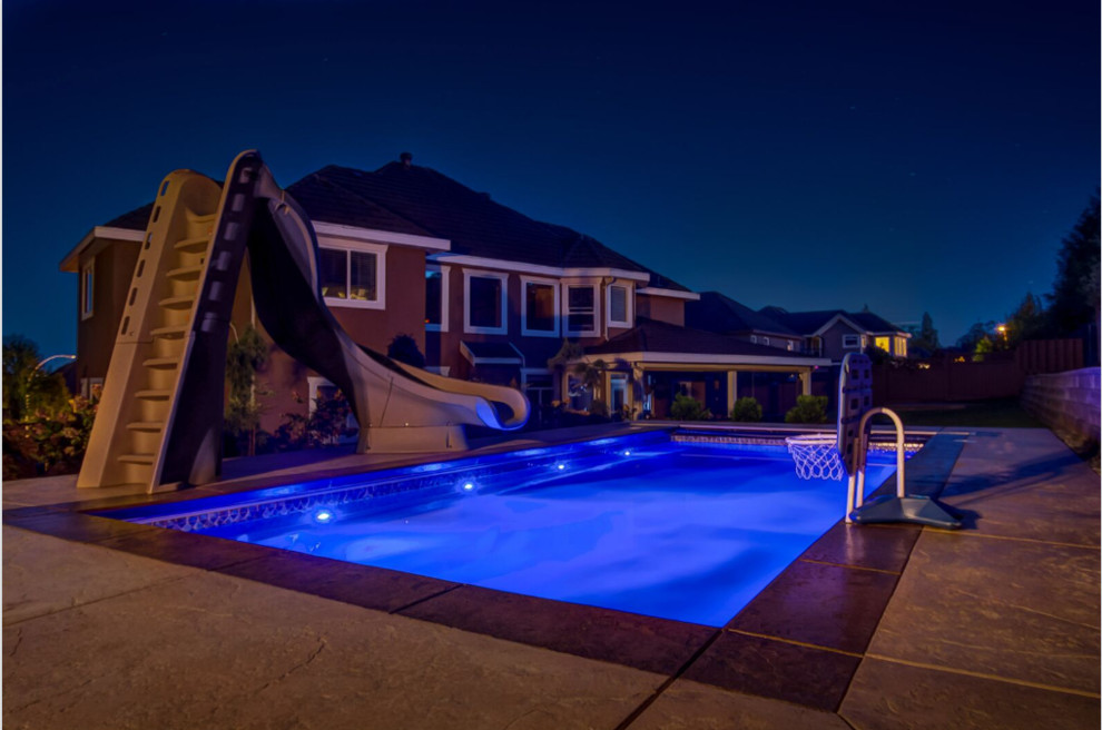 Foto di una piscina minimalista rettangolare di medie dimensioni e dietro casa con un acquascivolo e cemento stampato