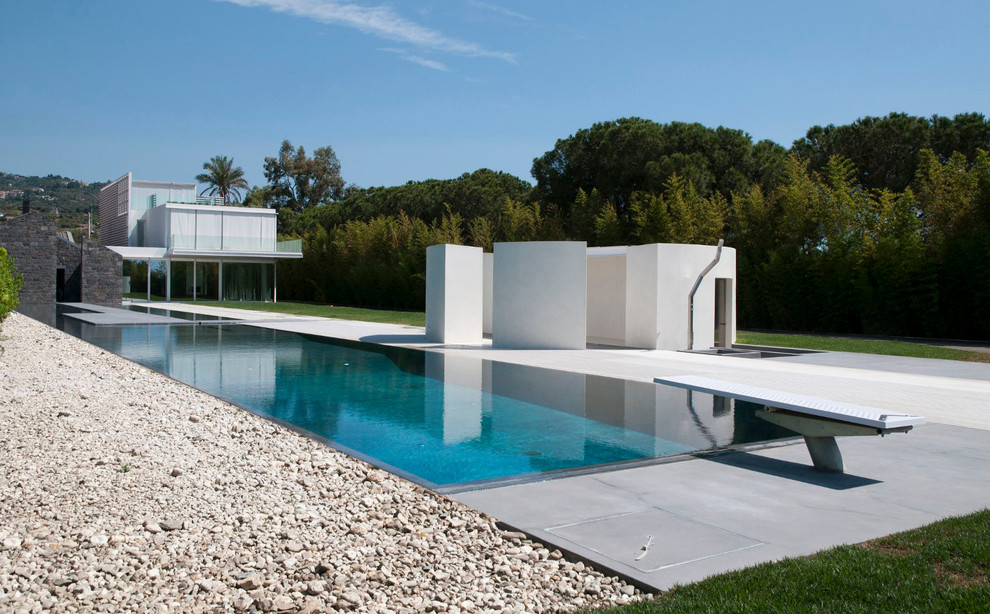 Immagine di una grande piscina a sfioro infinito minimalista personalizzata dietro casa con una dépendance a bordo piscina e pavimentazioni in cemento