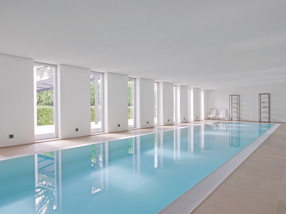 Cette image montre une très grande piscine intérieure design rectangle avec du carrelage.