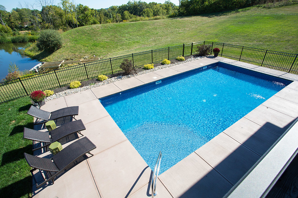Medium sized traditional back rectangular swimming pool in Cincinnati with concrete slabs.