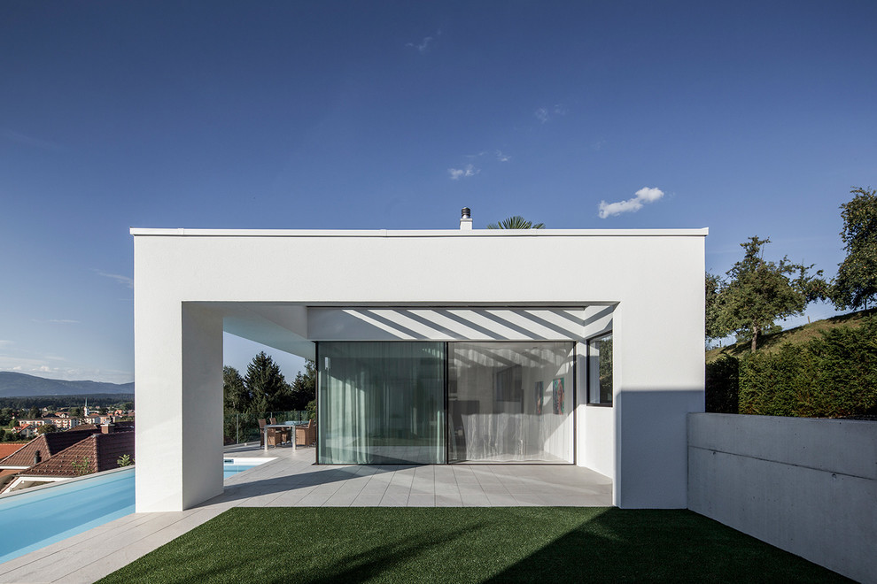 Modelo de piscina alargada minimalista extra grande rectangular en patio lateral con adoquines de hormigón