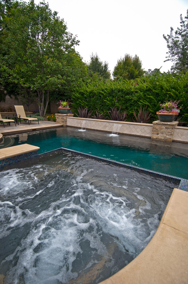 Esempio di una grande piscina monocorsia classica personalizzata dietro casa con una vasca idromassaggio e pavimentazioni in cemento