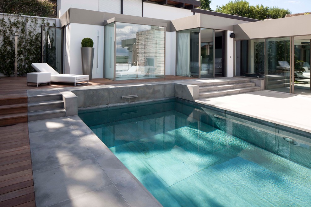 Diseño de piscina alargada contemporánea rectangular en patio trasero con losas de hormigón