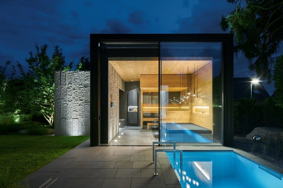 Пример оригинального дизайна: большой естественный, угловой бассейн на переднем дворе в современном стиле с домиком у бассейна и покрытием из каменной брусчатки