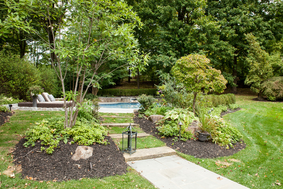 This is an example of a medium sized traditional back kidney-shaped swimming pool in Philadelphia with natural stone paving.