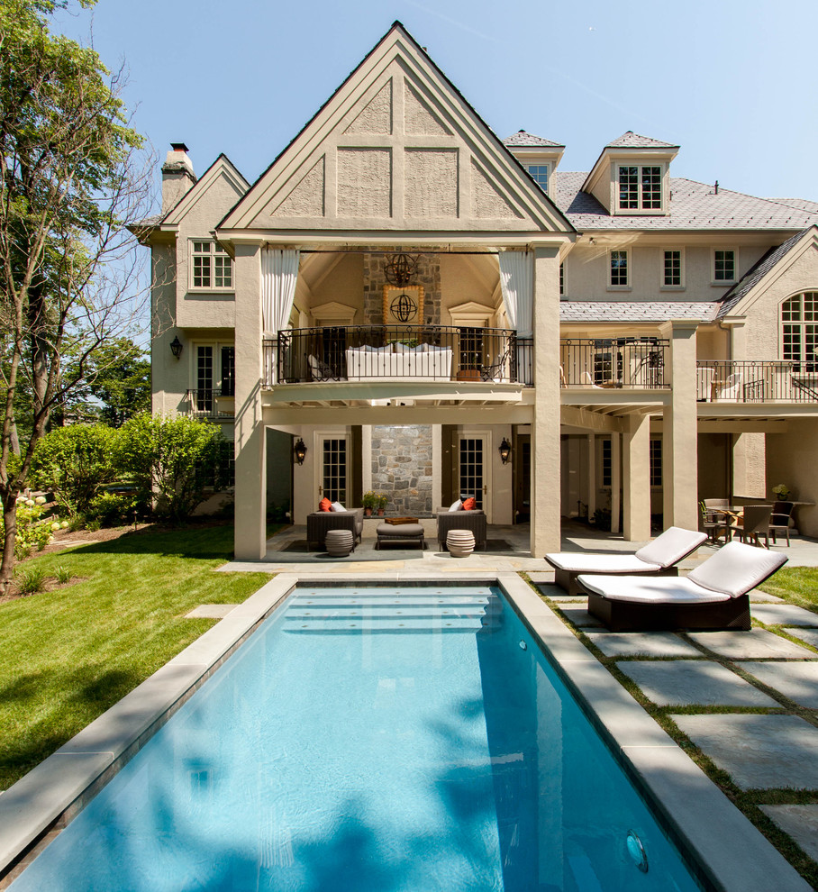 Ispirazione per un'ampia piscina monocorsia classica rettangolare dietro casa con pavimentazioni in pietra naturale