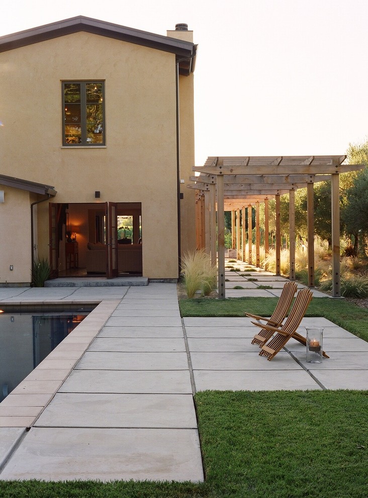 Modelo de piscina mediterránea de tamaño medio rectangular en patio trasero con losas de hormigón