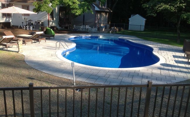 Imagen de piscina alargada clásica de tamaño medio a medida en patio trasero con adoquines de ladrillo