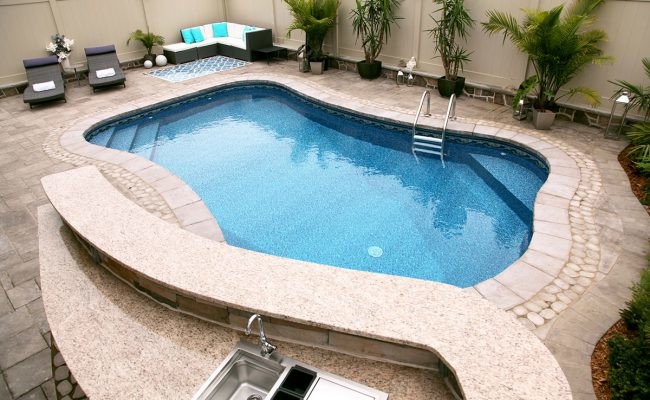 Imagen de piscina alargada tradicional de tamaño medio a medida en patio trasero con adoquines de piedra natural