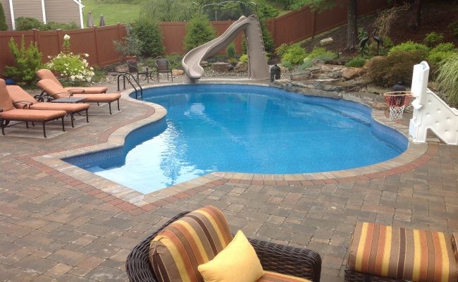 Foto di una piscina monocorsia tradizionale personalizzata di medie dimensioni e dietro casa con un acquascivolo e pavimentazioni in mattoni