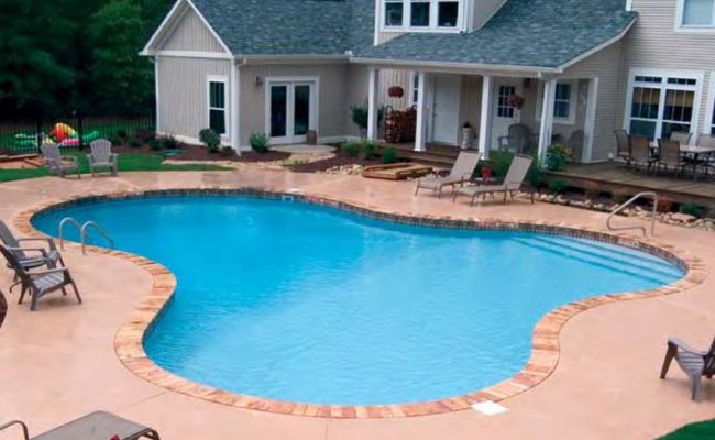 Ejemplo de piscina alargada clásica de tamaño medio a medida en patio trasero con adoquines de hormigón