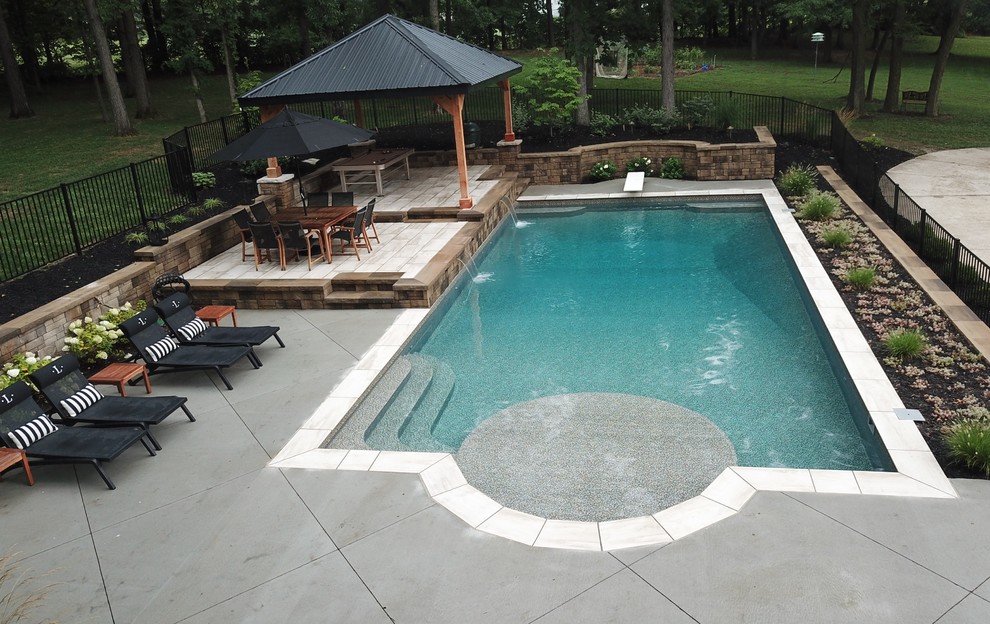 Diseño de piscina con fuente natural contemporánea grande rectangular en patio trasero con suelo de hormigón estampado