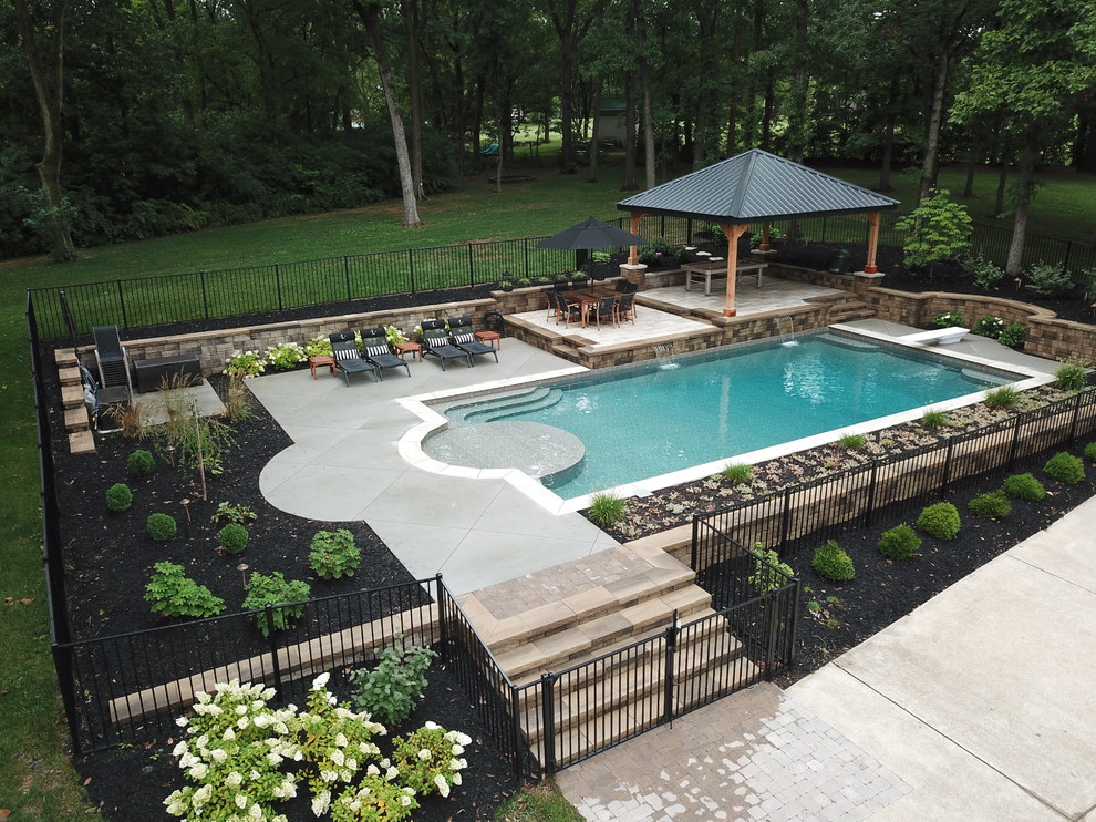Example of a large trendy backyard stamped concrete and rectangular natural pool fountain design in St Louis