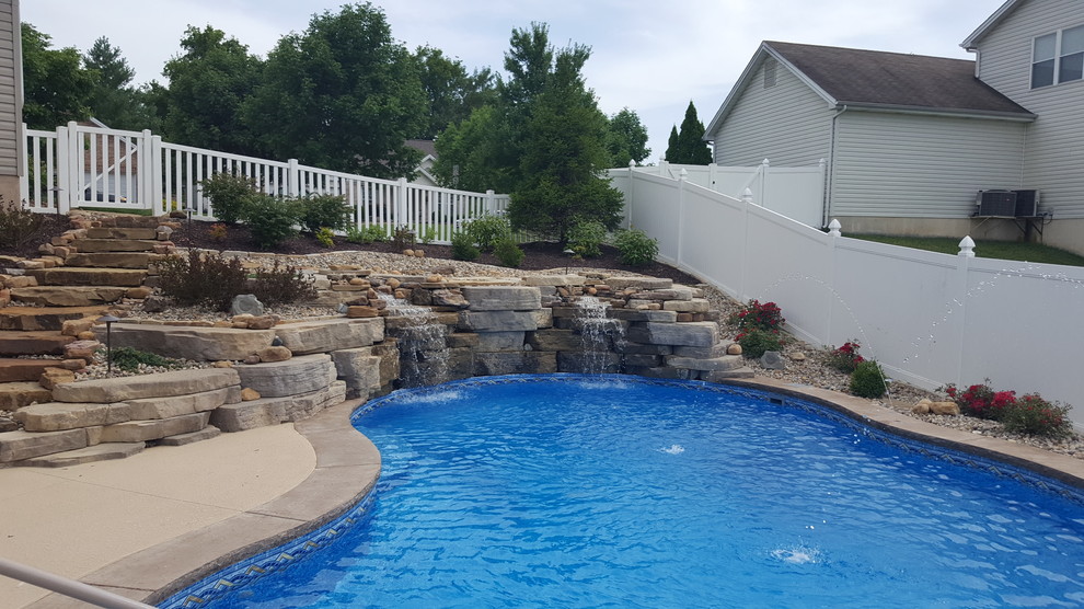 Foto de piscina con fuente actual de tamaño medio a medida en patio trasero con suelo de hormigón estampado