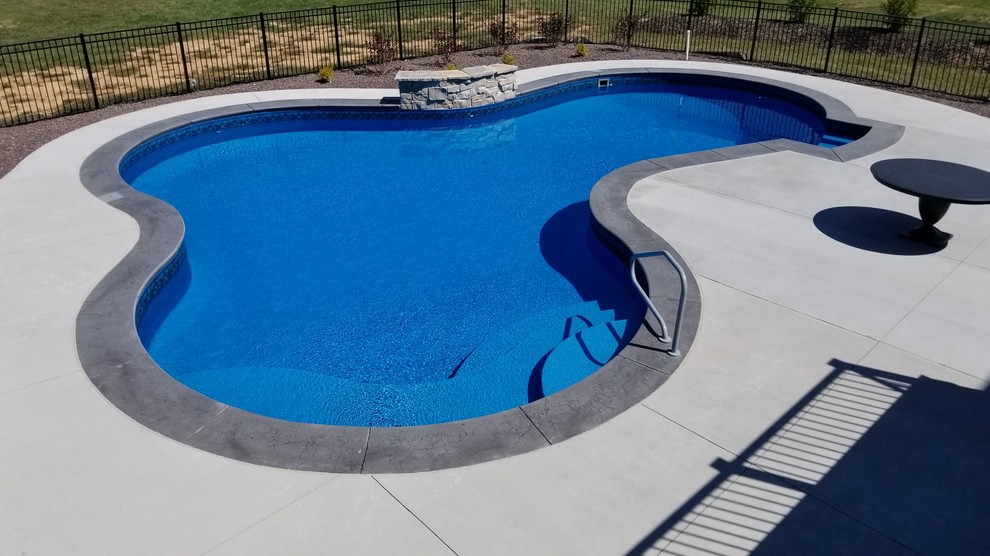 На фото: большой бассейн произвольной формы на заднем дворе в классическом стиле с покрытием из декоративного бетона с
