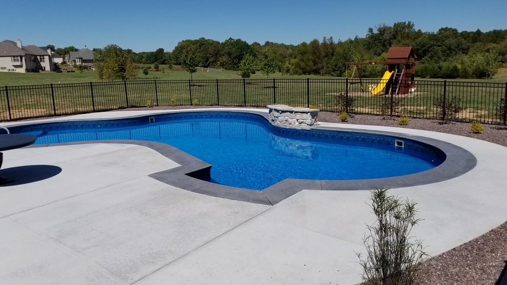 Photo of a large traditional back custom shaped swimming pool in St Louis with stamped concrete.