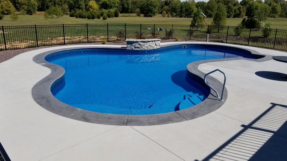 Design ideas for a large traditional back custom shaped swimming pool in St Louis with stamped concrete.