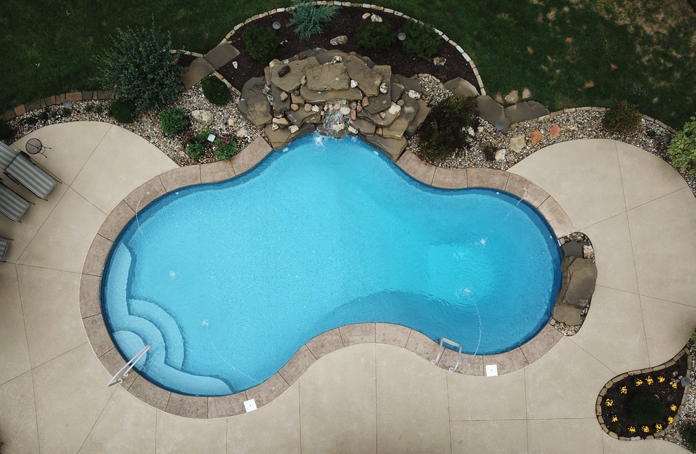 Modelo de piscina con fuente natural clásica de tamaño medio a medida en patio trasero con suelo de hormigón estampado