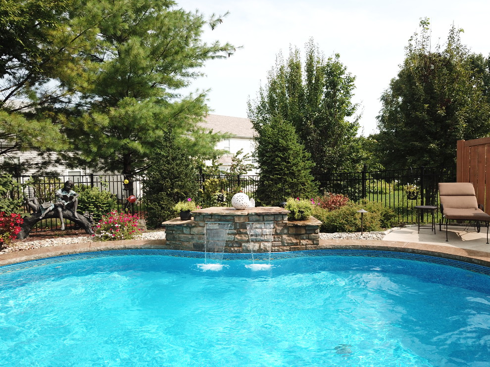 Imagen de piscina con fuente actual de tamaño medio a medida en patio trasero con suelo de hormigón estampado