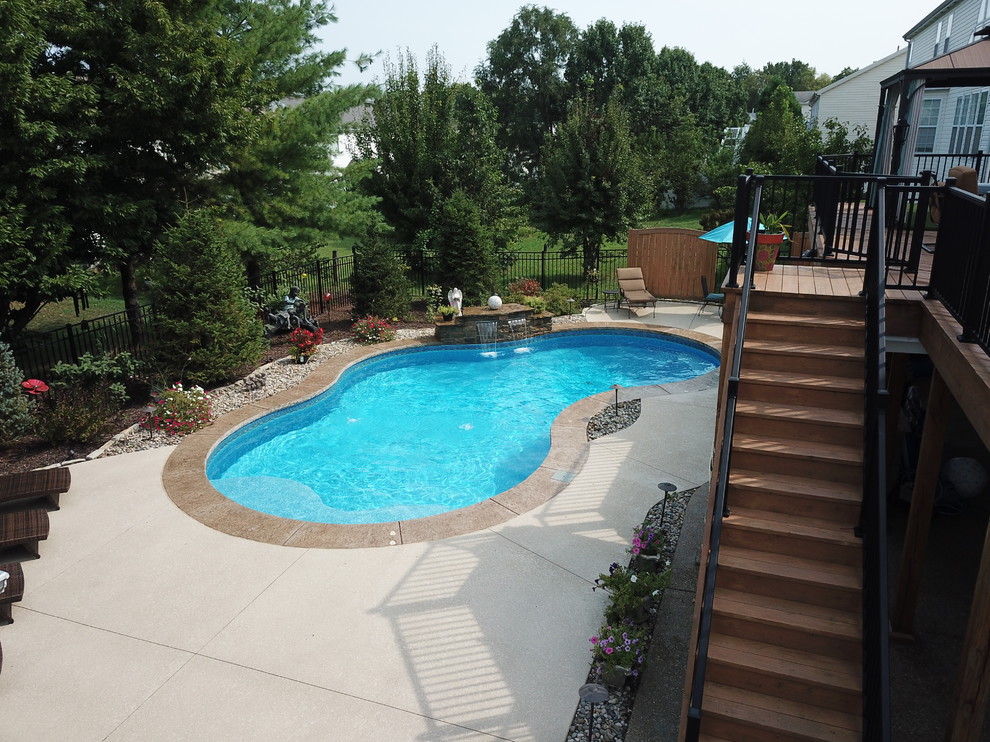 Modelo de piscina con fuente actual de tamaño medio a medida en patio trasero con suelo de hormigón estampado