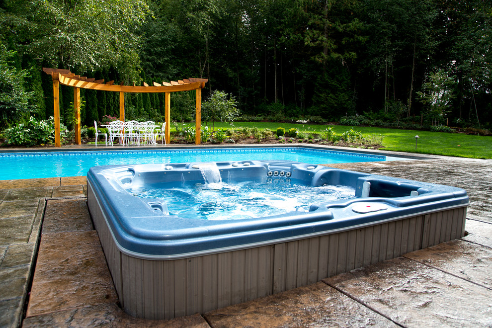 Ejemplo de piscinas y jacuzzis alargados clásicos grandes rectangulares en patio trasero con suelo de hormigón estampado