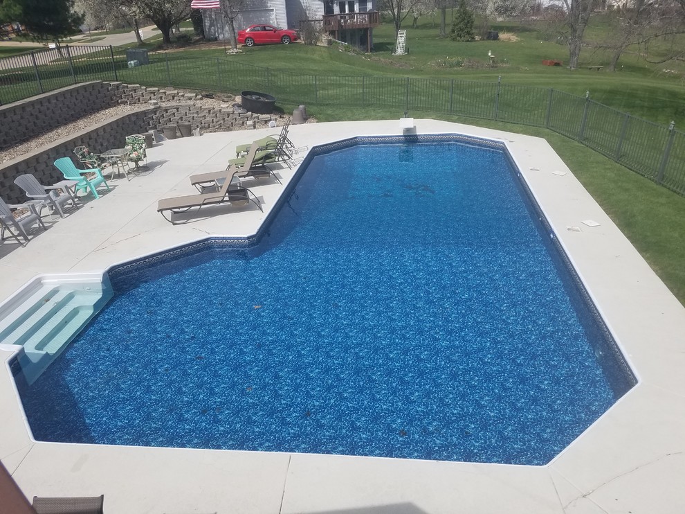 Modelo de piscina tradicional grande en forma de L en patio trasero con losas de hormigón