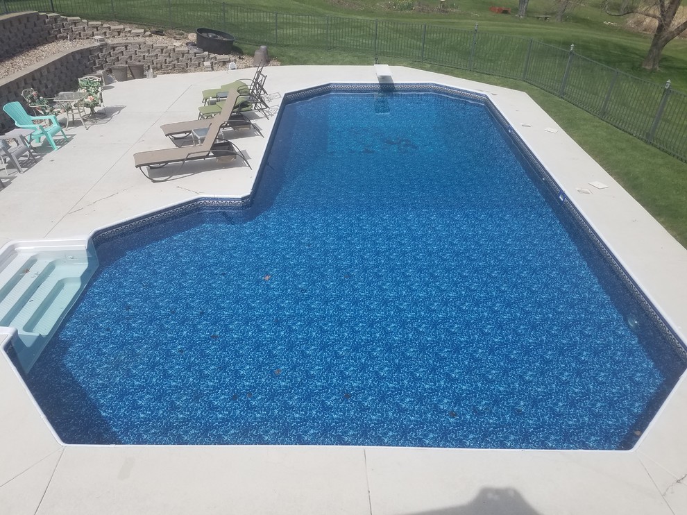 Cette image montre une grande piscine arrière traditionnelle en L avec une dalle de béton.