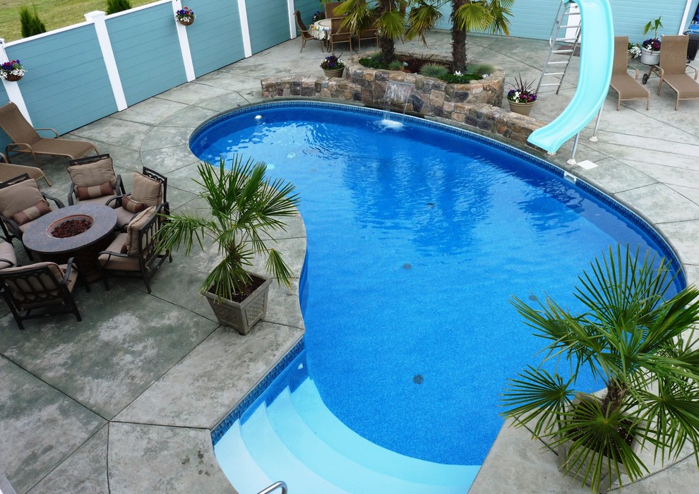 Foto de piscina con tobogán alargada tradicional pequeña tipo riñón en patio trasero con suelo de hormigón estampado