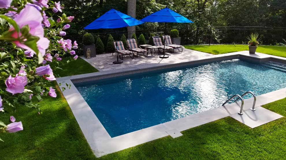 Foto de piscina alargada tradicional de tamaño medio rectangular en patio trasero con adoquines de hormigón