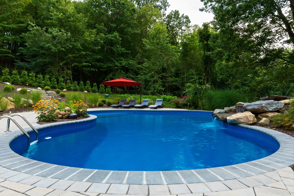 Foto de piscina con fuente clásica de tamaño medio a medida en patio trasero con adoquines de hormigón