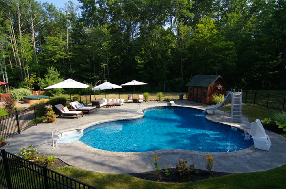 На фото: большой спортивный бассейн произвольной формы на заднем дворе с водной горкой и мощением тротуарной плиткой